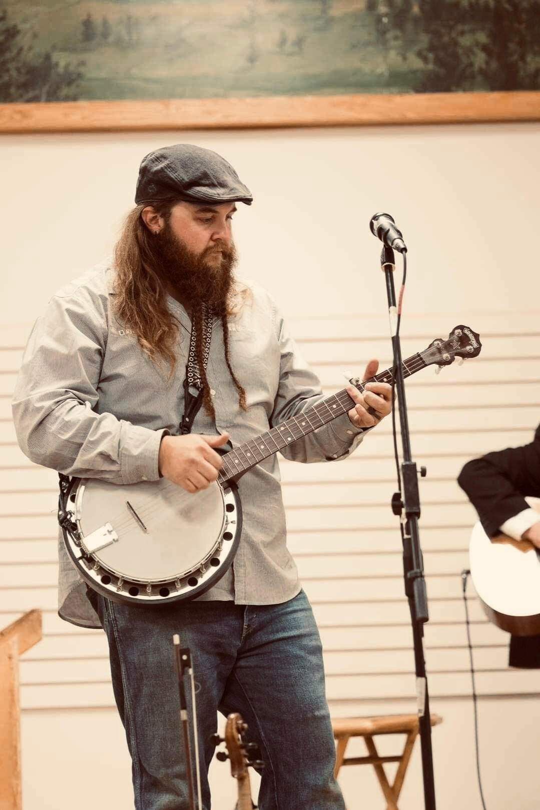 Tank, on stage in a blue shirt. He's holding a banjo, and there's a fiddle scroll sticking up at the bottom of the screen. Also, check out the mic. This guy can sing?
